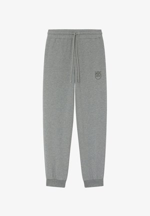 Sive trenirke izrađene od mekanog materijala, s elastičnim pojasom na kojem se može podesiti uzicom, sužene na gležnjevima i s malim logotipom u tonu.