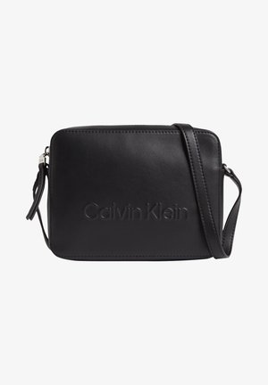 Sac bandoulière rectangulaire en cuir noir avec "Calvin Klein" embossé sur le devant et bandoulière réglable.