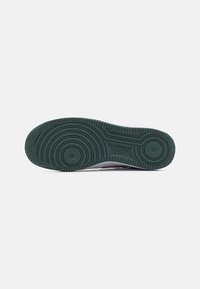Podeszwa sneakersów Nike w ciemnozielonej gumie, z teksturowanym wzorem zawierającym okrągłe i liniowe rowki dla lepszej przyczepności.