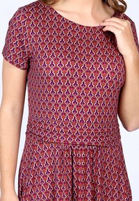 Kurzärmliges Kleid mit einem lila-rosa Muster, das wellenförmige Designs und kontrastierende Akzente zeigt. Aus flexiblem Stoff mit taillierter Passform gefertigt.