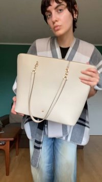 Béžová taška cez rameno vyrobená z hladkého materiálu, s hardware v zlatej farbe, dlhými popruhmi a jednoduchým obdĺžnikovým dizajnom.