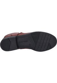 Bruine leren schoen met een zwart rubberen zool, voorzien van horizontale groeven voor grip en een geperst merkteken op de onderkant.