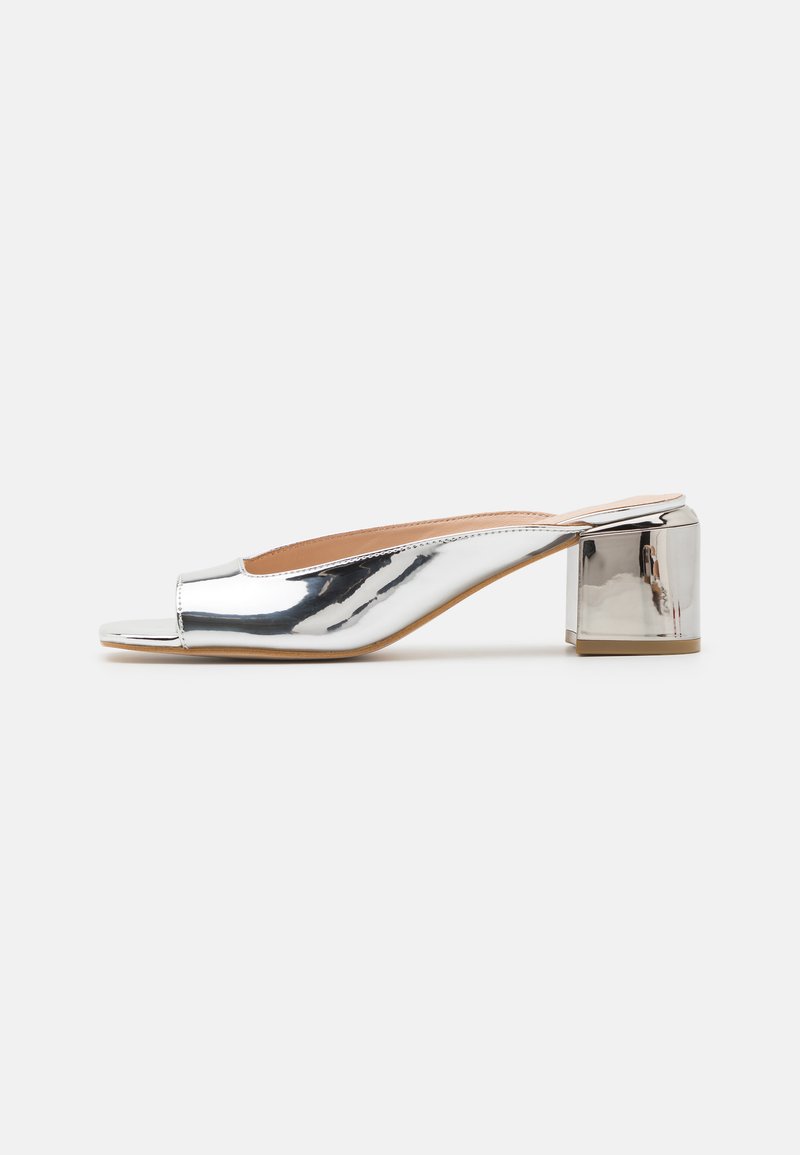 Mule con tacco a blocco open-toe in argento metallico. Superficie liscia e riflettente; design minimalista con silhouette curva.