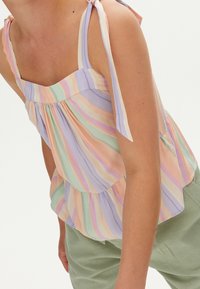 Kevyt, pastelliraidallinen toppi, jossa on neliömäinen pääntie, ohuet hihnat, jotka on solmittu olkapäille, ja kerroksittainen liehureunus.