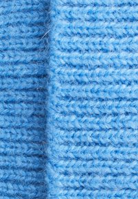 Light blue knitted fabric with a soft texture, featuring a ribbed pattern and visible fibers. The weave is dense, providing warmth.