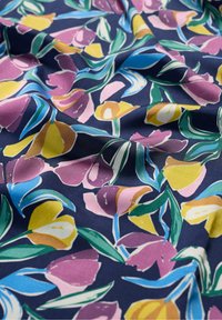 Floral fabric in navy with vibrant yellow, pink, and blue tulip patterns. Smooth texture with visible folds, emphasizing the design.