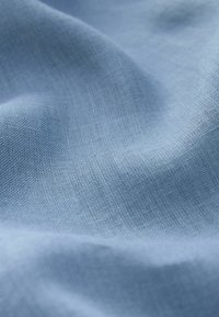 Tessuto azzurro chiaro con una superficie liscia e leggermente strutturata, caratterizzato da una fine trama e un drappeggio morbido, adatto per diverse applicazioni tessili.