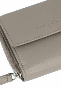 Portafoglio grigio in pelle compatto con pattina cucita, logo "PICARD" in rilievo e chiusura a zip con un pomello in pelle.