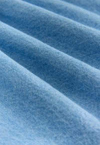 Tissu bleu clair avec une texture lisse, présentant de subtiles stries diagonales. Le matériau semble doux et finement tissé.