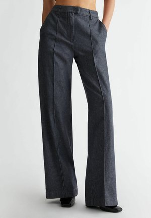 Wijdvallende broeken van donkerdenim met een rechte pasvorm, voorzien van verticale stiksels en zijzakken. Gaat goed samen met stijlvolle zwarte schoenen.