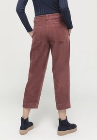 Konstruktionstygbyxor i en dammig rosafärg med cropped ben, med bakfickor och i kombination med marinblå ankelboots.