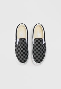 Fekete és szürke sakktáblaszerű slip-on cipők textil felsőrészsel, fehér gumitalppal és kontrasztos fekete szegéllyel a nyílás mentén.