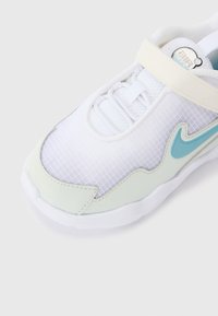 Baskets blanches en matériau mesh et cuir. Présente un accent vert mint clair et un design de swoosh bleu frappant. Fermeture à bande Velcro.