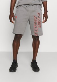 Shorts de sport gris en mélange de coton doux, avec une taille à cordon de serrage et un grand imprimé rouge "Under Armour" sur un côté.