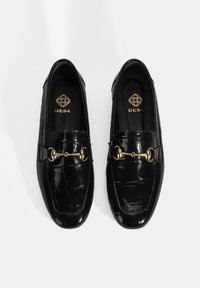 Zwarte leren loafers met krokodillenpatroon en een glanzende afwerking, voorzien van gouden hardware en stiklappen. Merk zichtbaar aan de binnenkant van de schoen.
