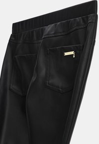 Črne hlače iz umetnega usnja z gladko teksturo, s širokim elastičnim pasom in dvema zadnjima žepoma, pri čemer je en označen z zlatim označevalnikom.