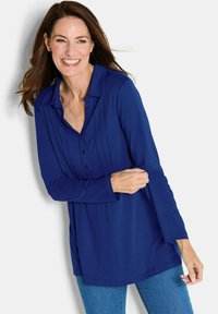 Marineblaue Langarmbluse mit Kragen, Knopfleiste und vertikalen Falten entlang der Vorderseite. Weicher Stoff und lockere Passform.