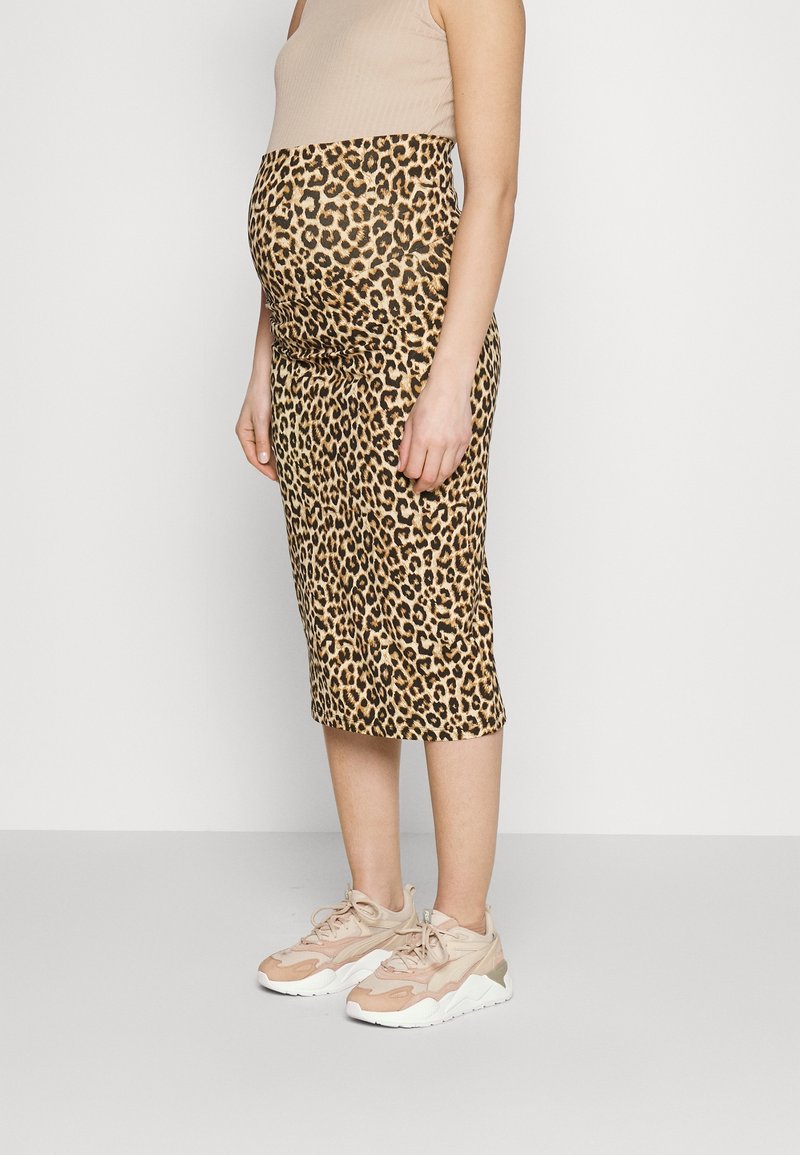 Jupe midi de maternité à imprimé léopard avec une ceinture élastique beige et une coupe ajustée, associée à des baskets de sport ton neutre.