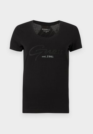 T-shirt nera a maniche corte con scollo rotondo. Presenta la scritta "Guess" in un carattere svolazzante e "est. 1981" stampato sotto in bianco a contrasto.
