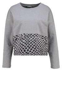 Felpa grigia cropped con un motivo a pois neri texturizzati nella parte inferiore anteriore. Progettata con una vestibilità morbida e maniche lunghe.