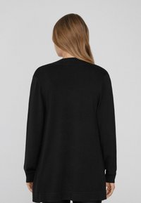 Schwarze Langarm-Cardigan mit lockerer Passform, Rundhals und gerippten Bündchen. Hergestellt aus weichem Stoff, zeichnet sich durch ein nahtloses Rückendesign aus.