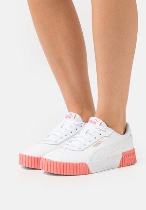 Białe sneakersy z fakturowaną skórzaną cholewką, różową gumową podeszwą oraz złotymi detalami logo po boku i na języku.