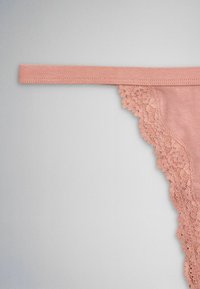 Pink lace-trimmed underwear strap and side panel on a neutral gray background, showing floral lace detail and smooth fabric.