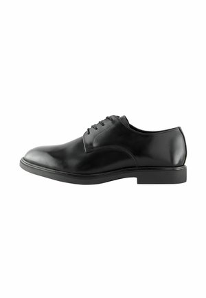 Zapato de vestir de cuero negro con un acabado suave, diseño de cordones, punta redonda y una suela de goma baja. Estilo minimalista sin patrones visibles.