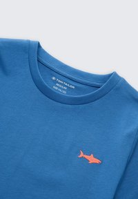 Blauw katoenen T-shirt met een reguliere pasvorm, met een oranje haaienlogo geborduurd op de linkerborst. Ronde halslijn en korte mouwen.