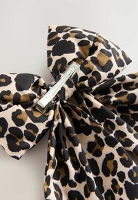 Preamă de păr cu imprimeu de leopard, din material textil, având modele negre, maronii și bej. Include un clips metalic argintiu lucios pentru fixare.