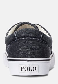 Ciemnoniebieskie tenisówki z białymi podeszwami i czarnymi akcentami, z zaokrąglonym noskiem i logo na pięcie. Teksturowana powierzchnia z detalami szwów.