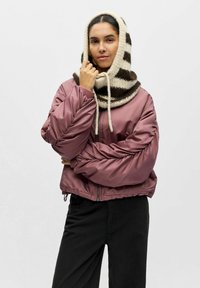 Veste aviateur matelassée et raccourcie en satin mauve avec des manches volumineuses, associée à une écharpe à capuche rayée crème et marron en maille.