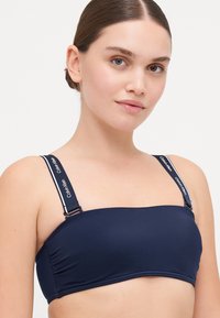 Navy bandeau badić s podesivim naramenicama s bijelim logotipom "Calvin Klein", glatkom tkaninom i prilagođenim dizajnom.