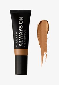 Smashbox Always On Cream Shadow dans un tube noir avec du texte argenté, présentant un échantillon de brun moyen sur un fond blanc, texture lisse.