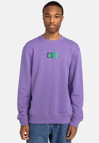 Purple sweatshirt with crew neck, featuring a small graphic design in black and green at the center. Ribbed cuffs and hem.