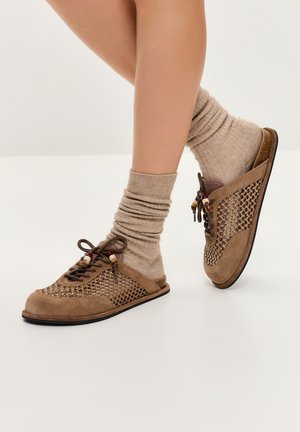 Brown suede shoes with mesh detailing, round toe, and lace closure, paired with beige ribbed socks, showcasing a casual design.