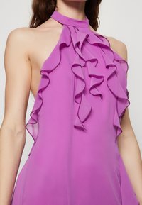 Halterneck dress in vibrant purple chiffon, featuring ruffled details along the bodice and a smooth, satin-like finish.