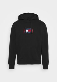 Sweat à capuche noir avec poche avant, capuche avec cordon de serrage, et patch du logo Tommy Jeans centré sur la poitrine en rouge, blanc et bleu.