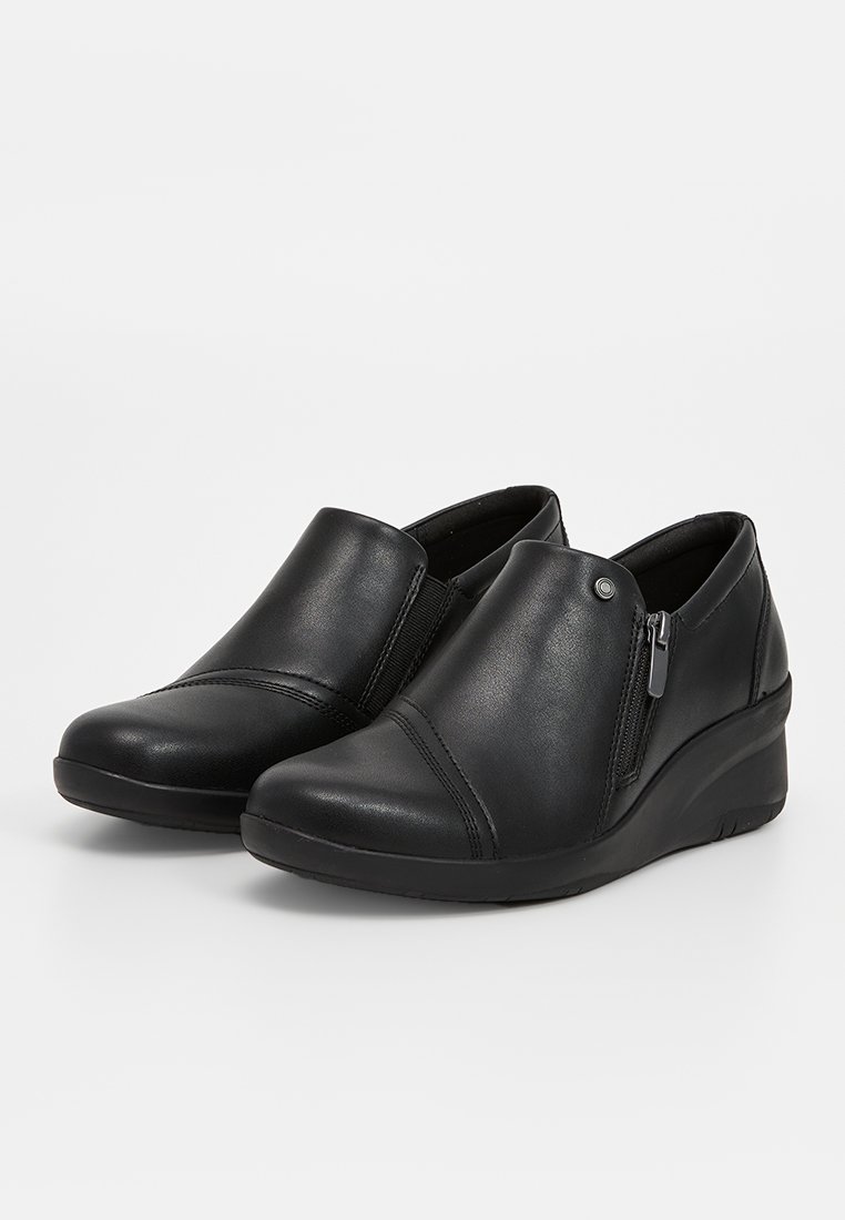 Svarta läder slip-on-skor med en slät yta, med en sidodragkedja, rund tå och en kilklack för ökad höjd.