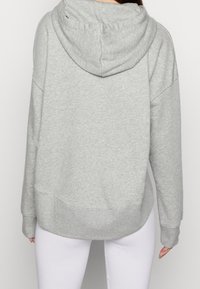 Grå hoodie med en avslappnad passform, med en mjuk textur och en dragkejda i huvan. Ärmar och fåll är ribbade.