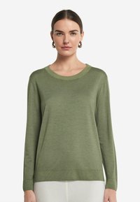 Zielony sweter z długim rękawem, okrągłym dekoltem i miękką fakturą. Żebrowane mankiety i dół dodają szczegółu prostemu fasonowi.