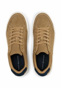 Sneakers in scamosciato tan con suole in gomma bianche, punta arrotondata e lacci frontali. Accenti blu navy sul tallone e sulla linguetta. Marchio visibile all'interno.
