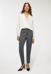 Biała koszula na guziki z długimi rękawami, zestawiona z szarymi, dopasowanymi spodniami i czarnymi szpilkami z ostro zakończonym noskiem. Miękka tkanina i uporządkowany krój.