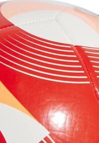 Fotbalový míč s hladkým, lesklým bílým povrchem a živými červenými a oranžovými zakřivenými liniemi. Má šité panely a zaoblený tvar.