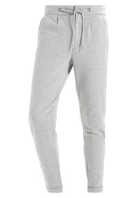 Pantalones de chándal grises hechos de un tejido suave y elástico. Presentan una cintura con cordón, bolsillos laterales y piernas ajustadas con dobladillos acampanados.