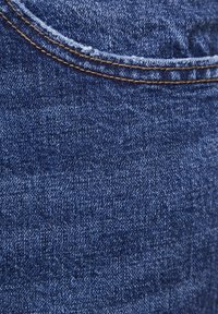 Tela de mezclilla azul oscuro con ligera textura, presenta costuras claras en contraste y una superficie lisa. Sin patrones ni diseños visibles.