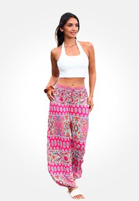 Top corto bianco con scollatura a ferma abbinato a pantaloni larghi rosa e blu con un motivo vivace e disegni intricati, caratterizzati da una vestibilità rilassata.