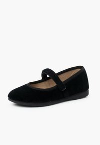 Zapato Mary Jane de terciopelo negro con suela plana, puntera redondeada y una correa de tela sobre el empeine, que cuenta con un suave forro interior.