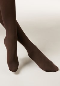 Collants opaques marron avec une texture lisse, un design ajusté et un orteil sans couture. Le tissu semble extensible et moulant.