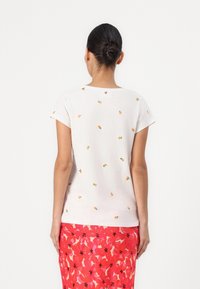 White short-sleeve t-shirt with orange and green fruit embroidery. Smooth texture and relaxed fit. Back view shows neckline detail.